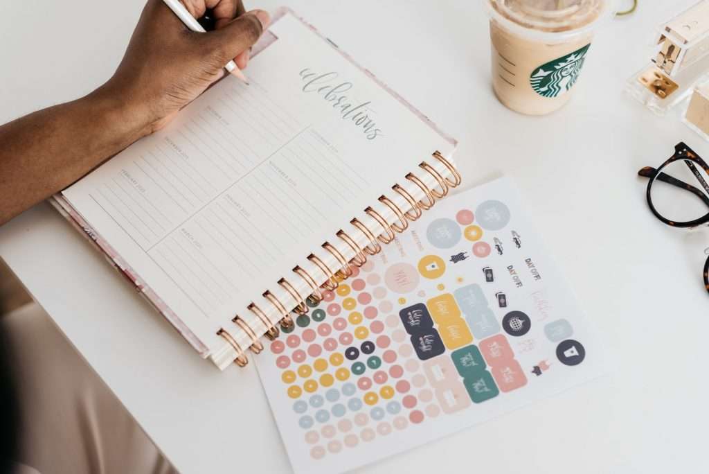 person writing on a life planner at the table